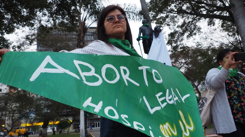 Mujer con una banderola que dice "aborto legal".