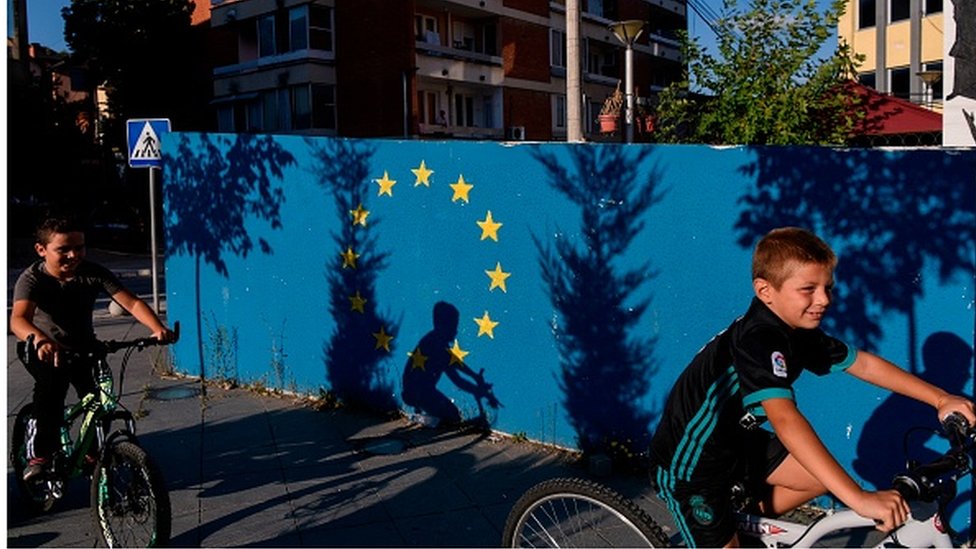 Dečaci na biciklu pored murala sa zvezdama zastave Evropske unije