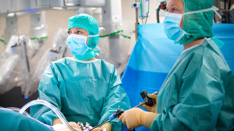 Two surgeons in an operating room during a hysterectomy.