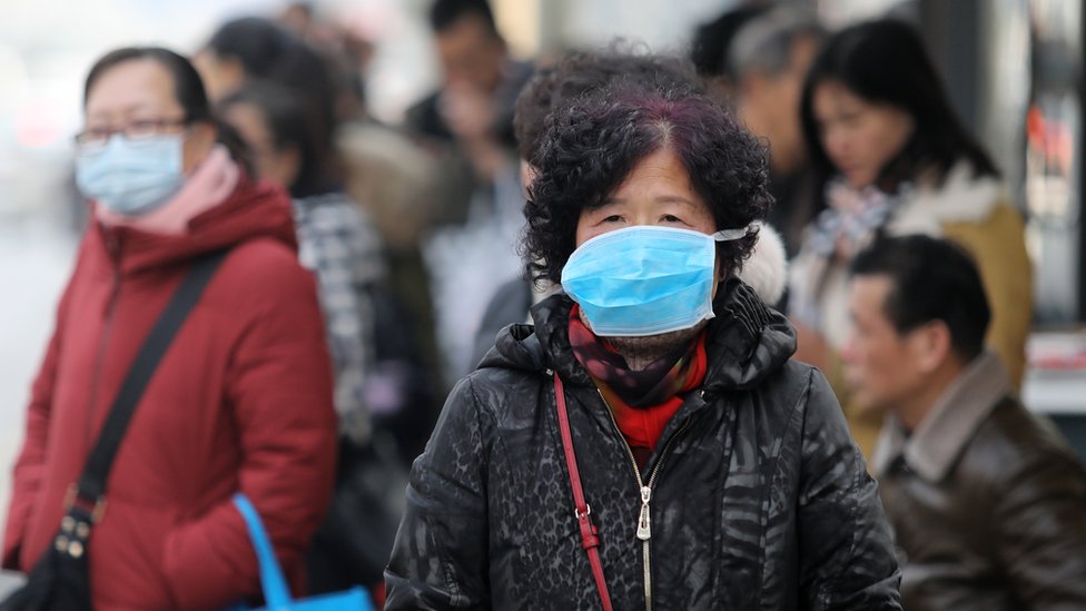 Chinese residents wear masks at a bus station near the closed Huanan Seafood Wholesale Market