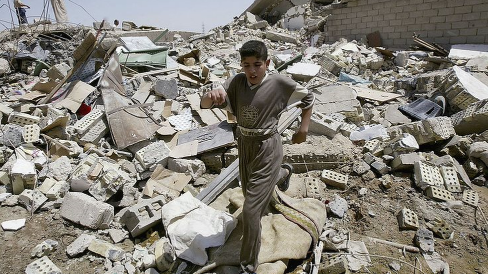 A boy walks through rubble in the Iraqi city of Fallujah in 2004