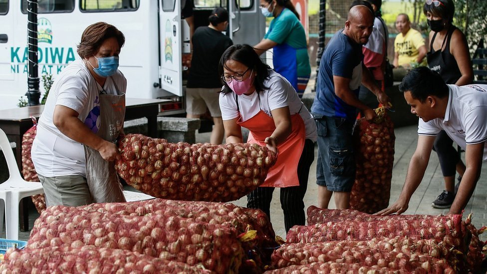 Personas cargando bolsas de cebollas en Quezon City, Manila, Filipinas el 10 de enero de 2023