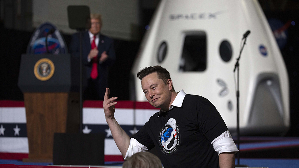 Elon Musk con Donald Trump de fondo