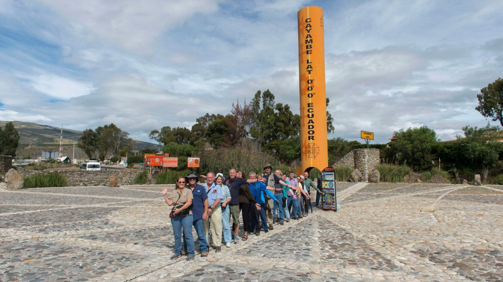 Turistas con un pie en el hemisferio norte y el otro, en el hemisferio sur en el monumento del ecuador de Quitsato y reloj de sol cerca de Cayambe, cerca de Quito.