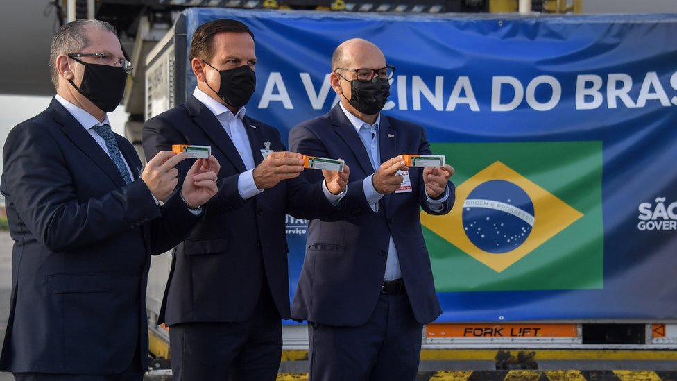 El gobernador de Sao Paulo, Joao Doria, el secretario de salud de Sao Paulo, Dr. Jean Gorinchteyn, y el director del Instituto Butantan, Dimas Covas, junto a un contenedor con dosis de CoronaVac en el aeropuerto de Sao Paulo.
