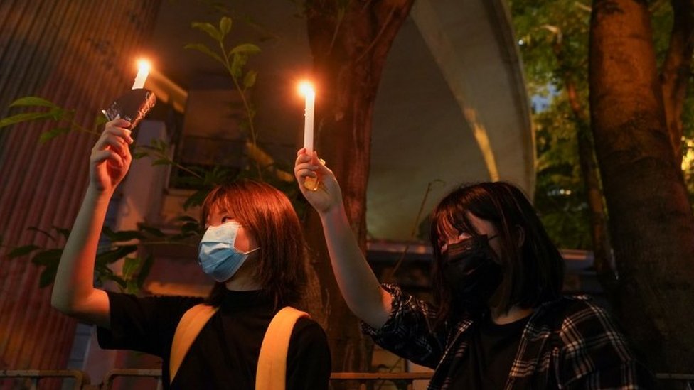 Dos mujeres levantan velas en el parque Victoria de Hong Kong.