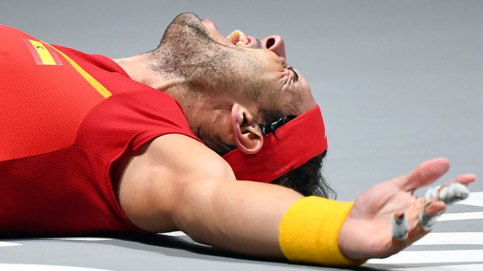 Rafael Nadal celebra la victoria en el piso de la cancha de tenis