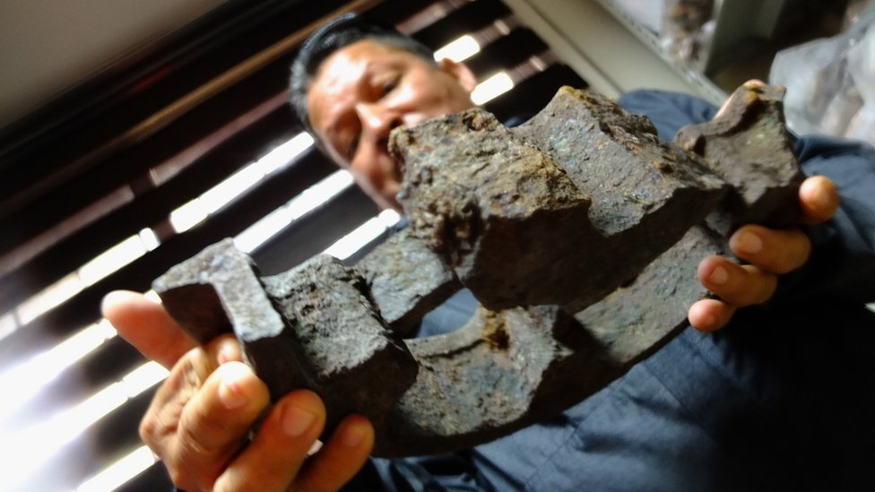 Eddy Becerra muestra los restos de una antigua rueda que se desplazaba por los rieles del ingenio al puerto.