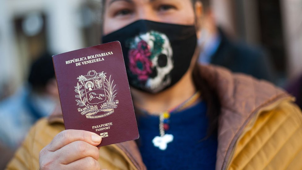 Una mujer muestra el pasaporte venezolano