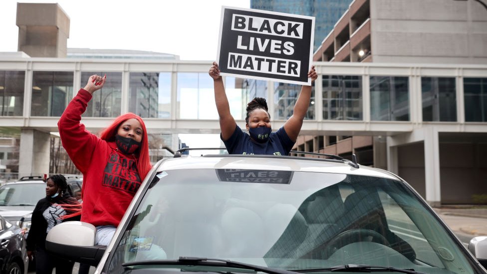 Dos jóvenes levantan una pancarta que reza "Black Lives Matter", tras conocerse el veredicto contra el exagente de policía Derek Chauvin.