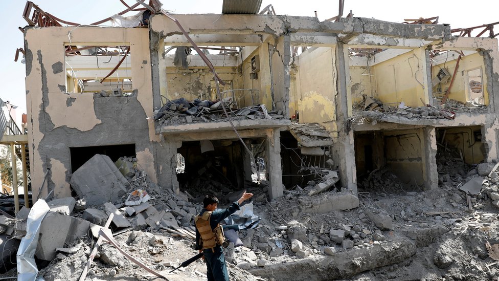 Офицер службы безопасности Афганистана охраняет место взрыва бомбы 7 августа в Кабуле, где стоит выдолбленное здание