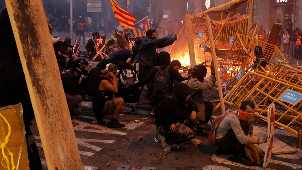 Protesters use fences as a barricade during clashes near police headquarters in Barcelona, on October 18, 2019