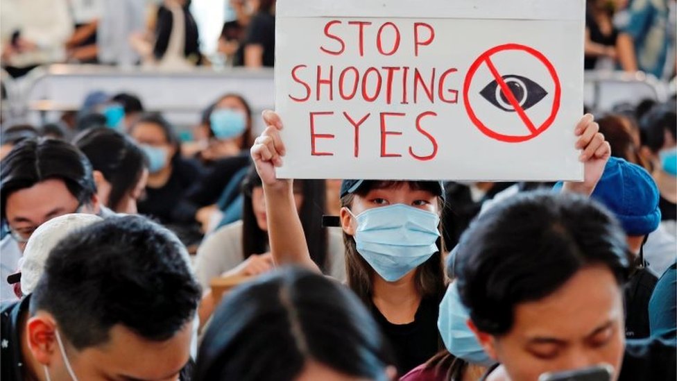 A protester in the airport holds a sign that says