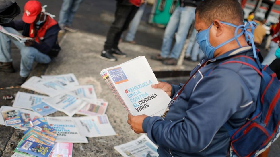 Un hombre lee la prensa en Venezuela en marzo con una mascarilla.