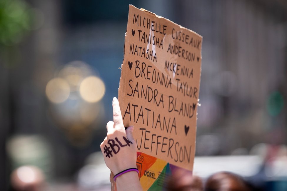 Протестующий в Нью-Йорке держит табличку с именем Ататьяны Джефферсон