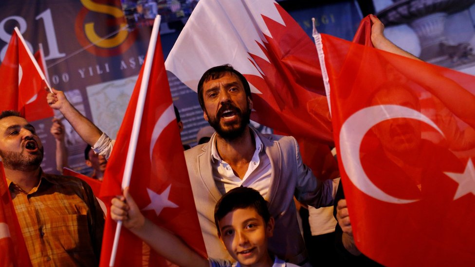 Люди выкрикивают лозунги, держа флаги Турции и Катара во время демонстрации в пользу Катара в Стамбуле, Турция (7 июня 2017 г.)
