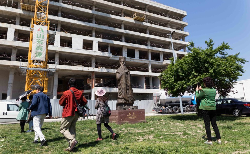 Kineski turisti prolaze pored statue Konfučija ispred mesta gde je nekada bila ambasada