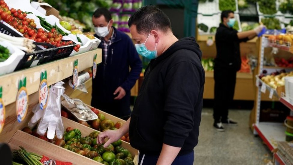 People wearing masks choose vegetables in a supermarket in Madrid, Spain. Photo: 14 March 2020