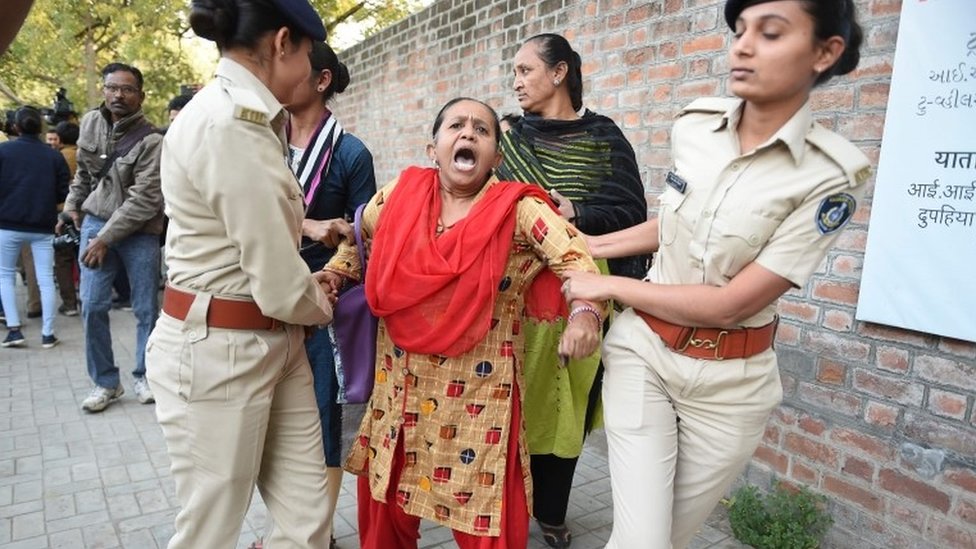 Сотрудники полиции Гуджарата задерживают демонстранта во время акции протеста против законопроекта о внесении поправок в закон о гражданстве, принятого правительством Индии, возле Индийского института управления (IIM) в Ахмедабаде в понедельник