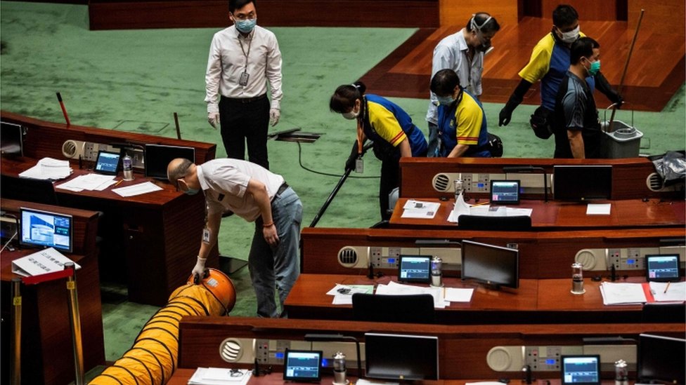 Рабочие убирают секцию в главной палате Законодательного совета после того, как законодатели вылили жидкость во время третьего чтения законопроекта о национальном гимне в Гонконге 4 июня 2020 г.