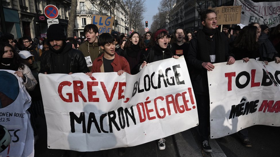 Протестующий держит плакат с надписью «Забастовка, блокада: Макрон вон!» Во время демонстрации в Париже 24 января 2020 г.