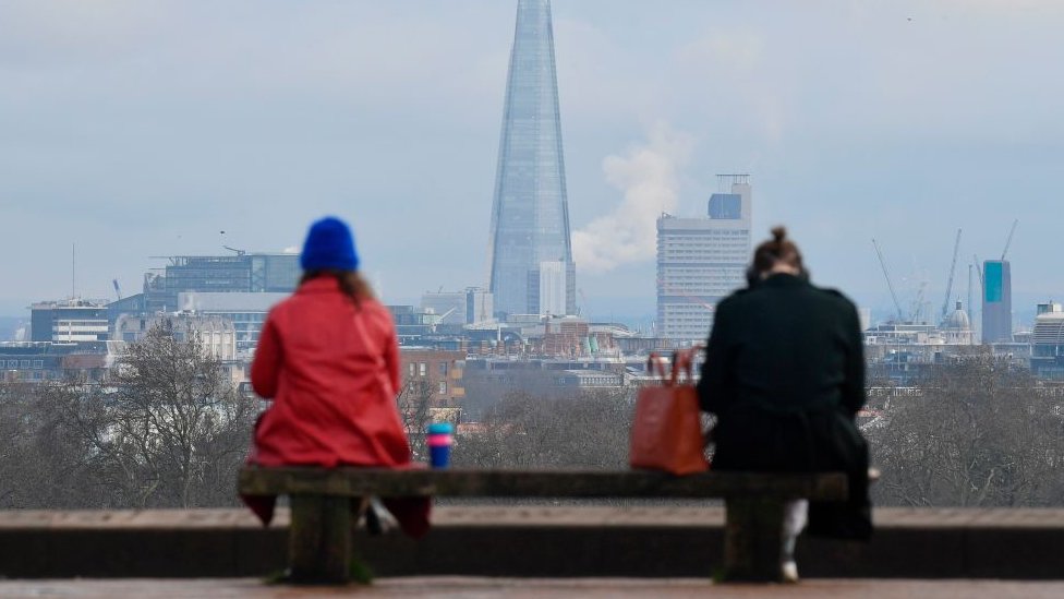 Duas pessoas sentadas enquanto adotam o distanciamento social entre elas em Londres, no Reino Unido