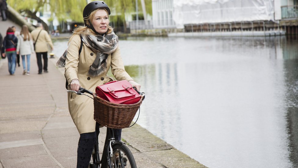 Woman riding her bike to work by a canal