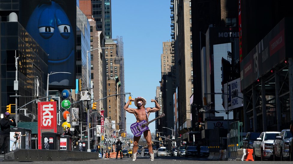 Незначительная нью-йоркская знаменитость, которая позирует для туристических фотографий в образе Обнаженного ковбоя в маске на почти безлюдной Таймс-сквер