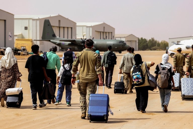 اشتباكات السودان: المعارك مستمرة وبريطانيا تنفذ آخر رحلة إجلاء لرعاياها 2 مواطنون بريطانيون يسيرون نحو طائرة تابعة لسلاح الجو الملكي البريطاني، أثناء رحلة إجلاء إلى قبرص، في قاعدة وادي سيدنا الجوية في السودان، 27 أبريل/نيسان 2023.