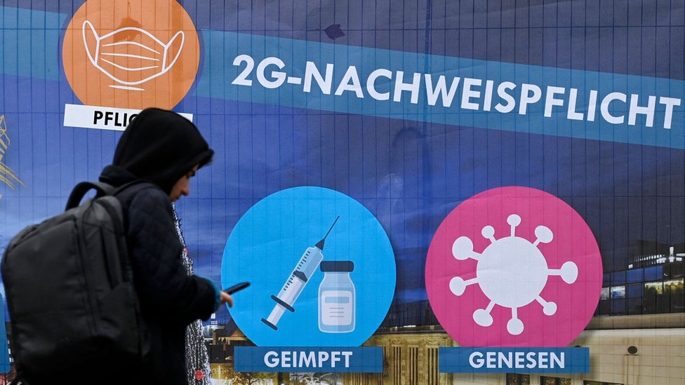A man walks past a placard which indicates the so-called 2G rule (vaccinated or recovered from Covid-19) for the Christmas market in the city of Dortmund, western Germany on December 1, 2021.