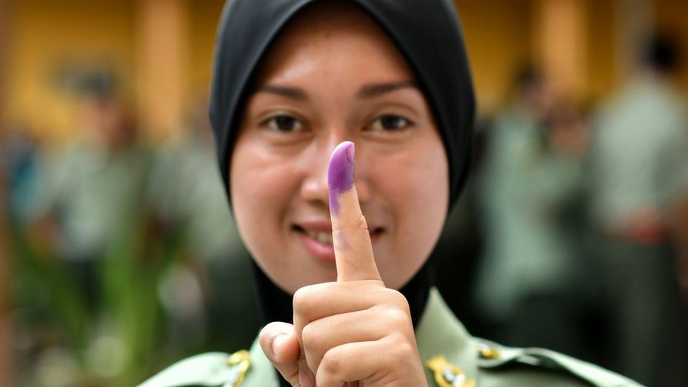 Mujer muestra su dedo pintado de violeta.