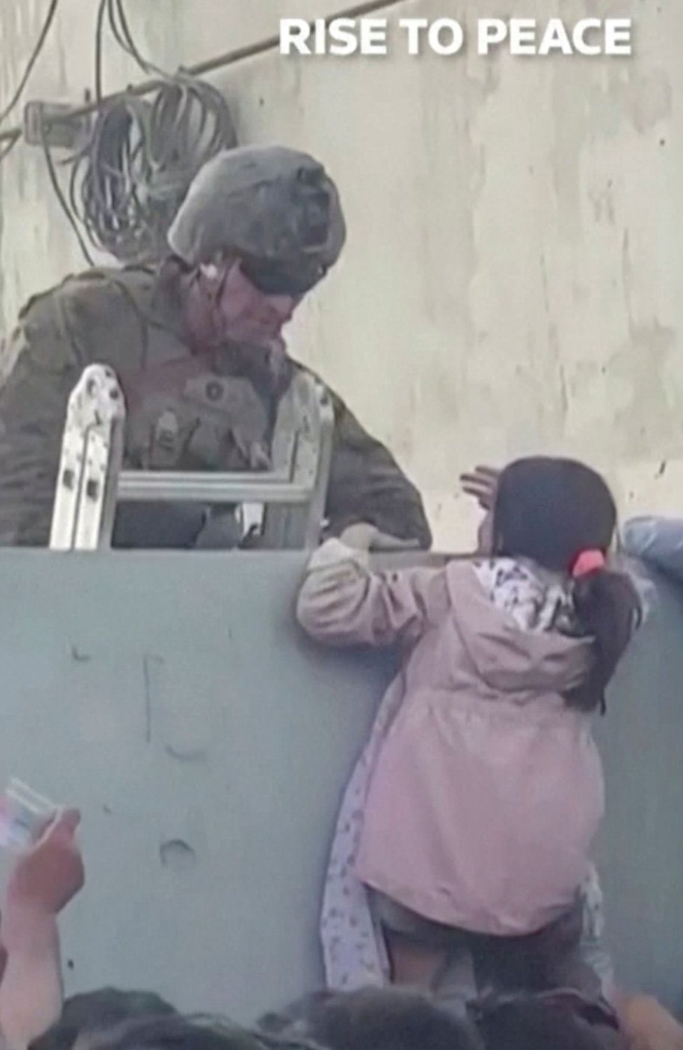 Una niña recibe asistencia para subir el muro del aeropuerto de Kabul