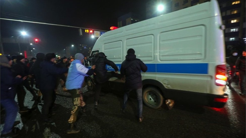 People attack a police minivan during a protest against LPG