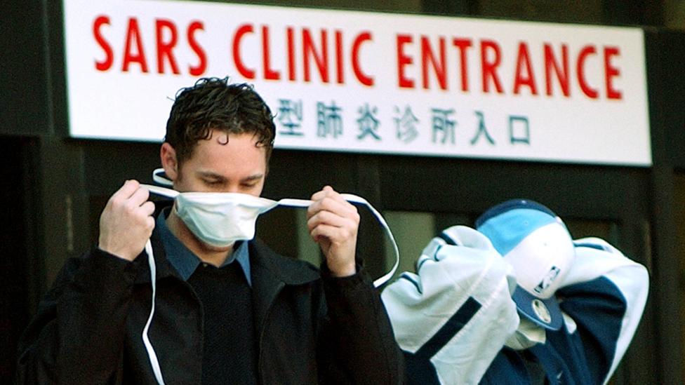 Seorang pria mengenakan masker di depan pintu masuk klinik Sars.