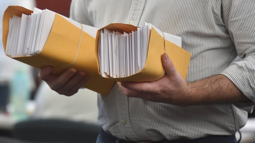 أحد العاملين في هيئة الانتخابات في ولاية بنسلفانيا يحمل بطاقات اقتراع مرسلة عبر البريد