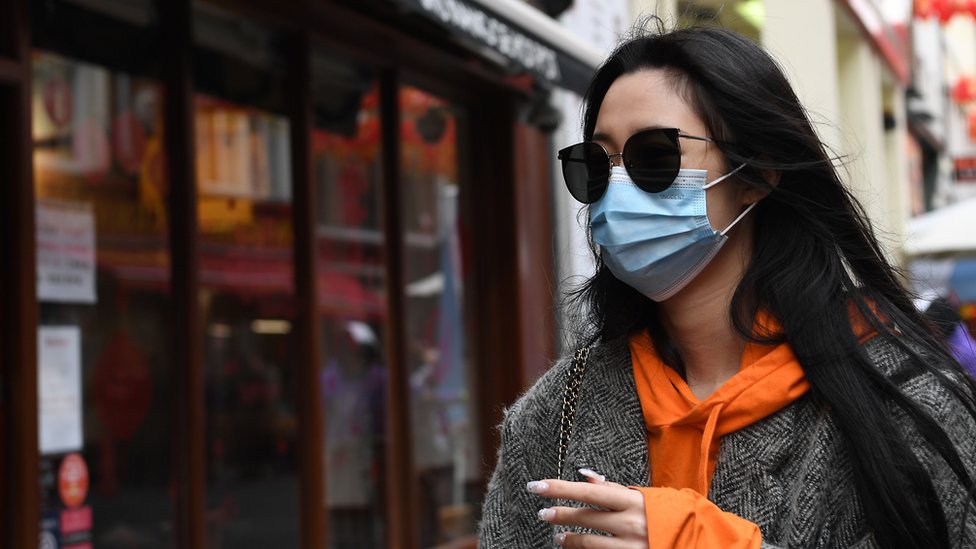 Женщина носит маску для лица в китайском квартале в Лондоне, Великобритания, 4 февраля 2020 года. Китайский квартал Лондона ощущает воздействие коронавируса, поскольку в ресторанах наблюдается снижение количества посетителей после подтверждения новых случаев коронавируса в Великобритании.
