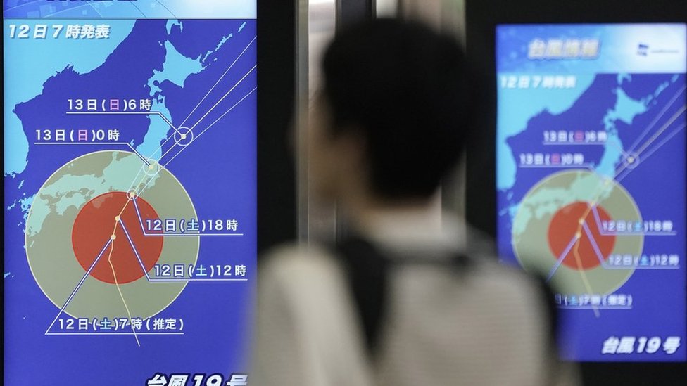 Un pasajero del ferrocarril mira las pantallas que muestran el tifón acercándose a Japón Un pasajero del ferrocarril mira las pantallas que muestran el tifón acercándose a Japón