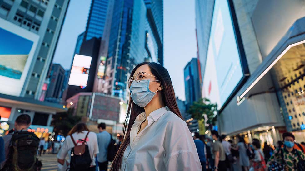 香港銅鑼灣鬧市一位戴著口罩的女士走過