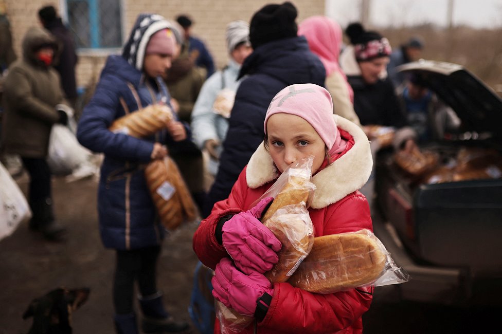 Desetogodišnja Anatasija drži vekne hleba koje joj je dao volonter, Herson