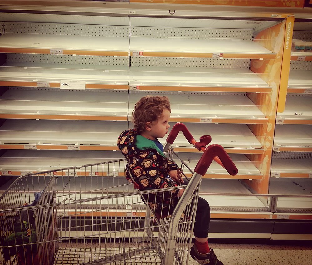 Child next to empty shelves in supermarket