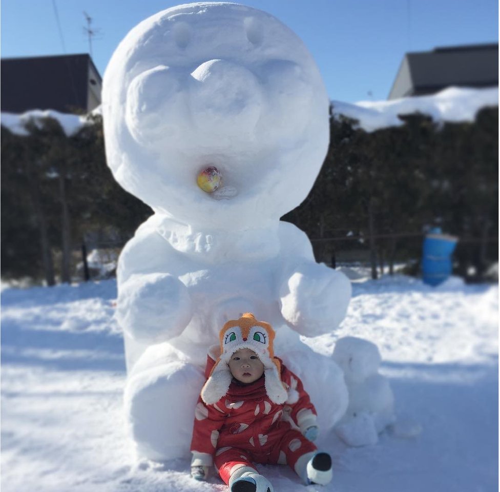 Снежный персонаж Анпанман, под которым сидит ребенок.