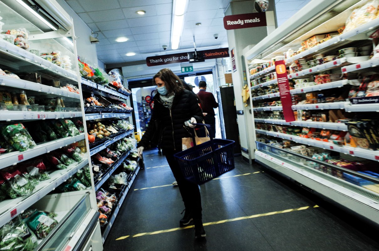 Woman in mask examines produce on shelves