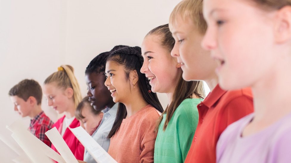 A group of teenagers singing from sheets