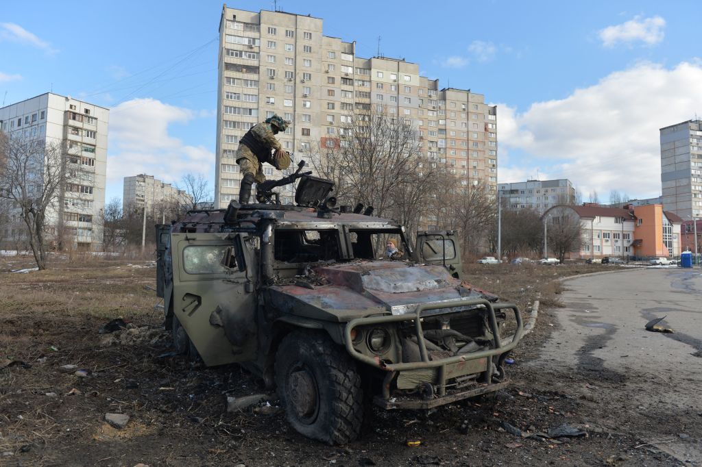 Um soldado de defesa territorial ucraniano examina um veículo militar russo queimado em Kharkiv