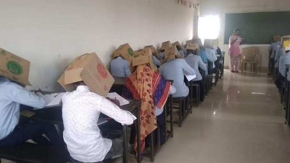 Students wearing boxes on their heads in exam