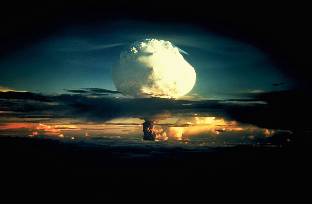 Una nube en forma de hongo blanca ondulante, moteada de naranja, atraviesa una capa de nubes durante la Operación Ivy, la primera prueba de una bomba de hidrógeno, en el atolón Enewetak en las Islas Marshall.