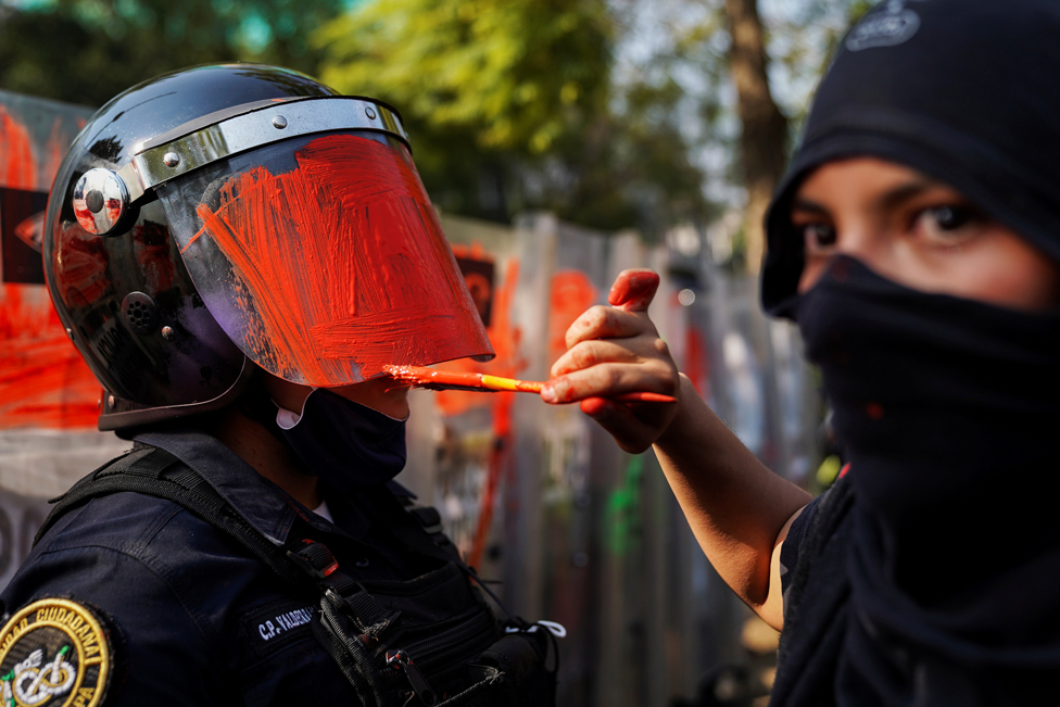 A demonstrator paints the helmet visor of a riot police officer, in Mexico City, Mexico, 11 November 2020
