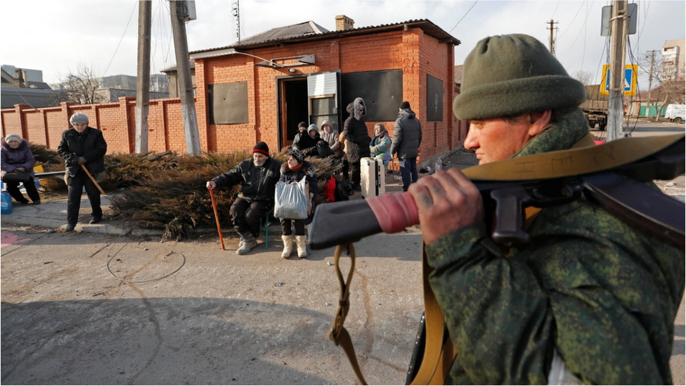 Residents in Mariupol watched by a pro-Russian guard