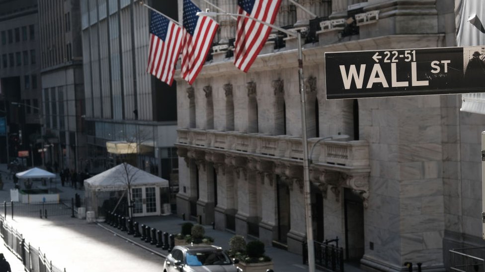 Нью-Йоркская фондовая биржа с знаком Уолл-стрит на переднем плане.