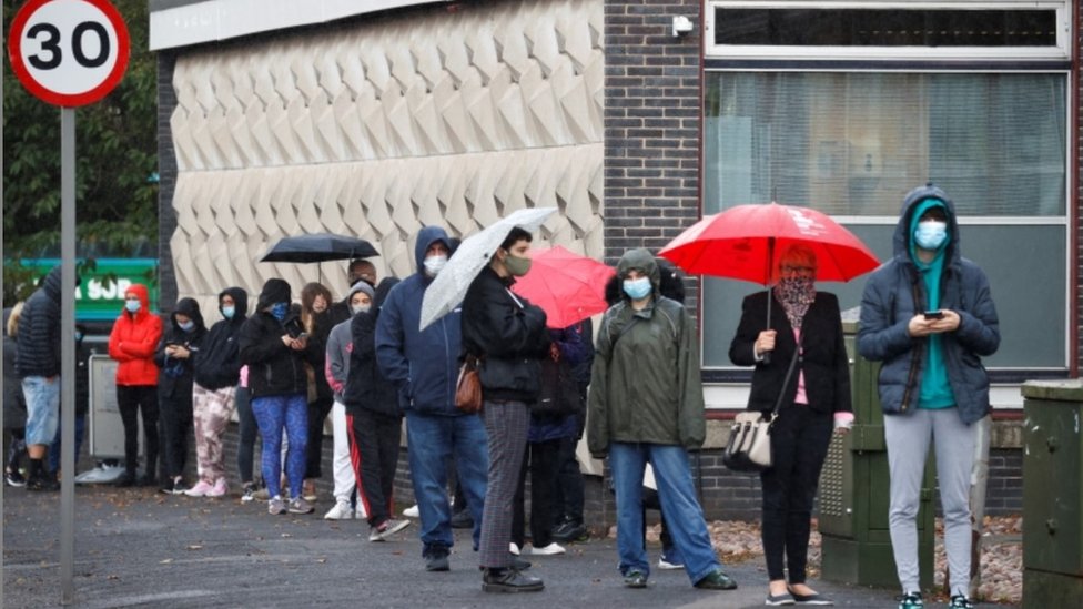Люди выстраиваются в очередь возле тестового центра на коронавирус в библиотеке Аллертона в Ливерпуле на фоне растущих случаев заболевания в некоторых частях Англии